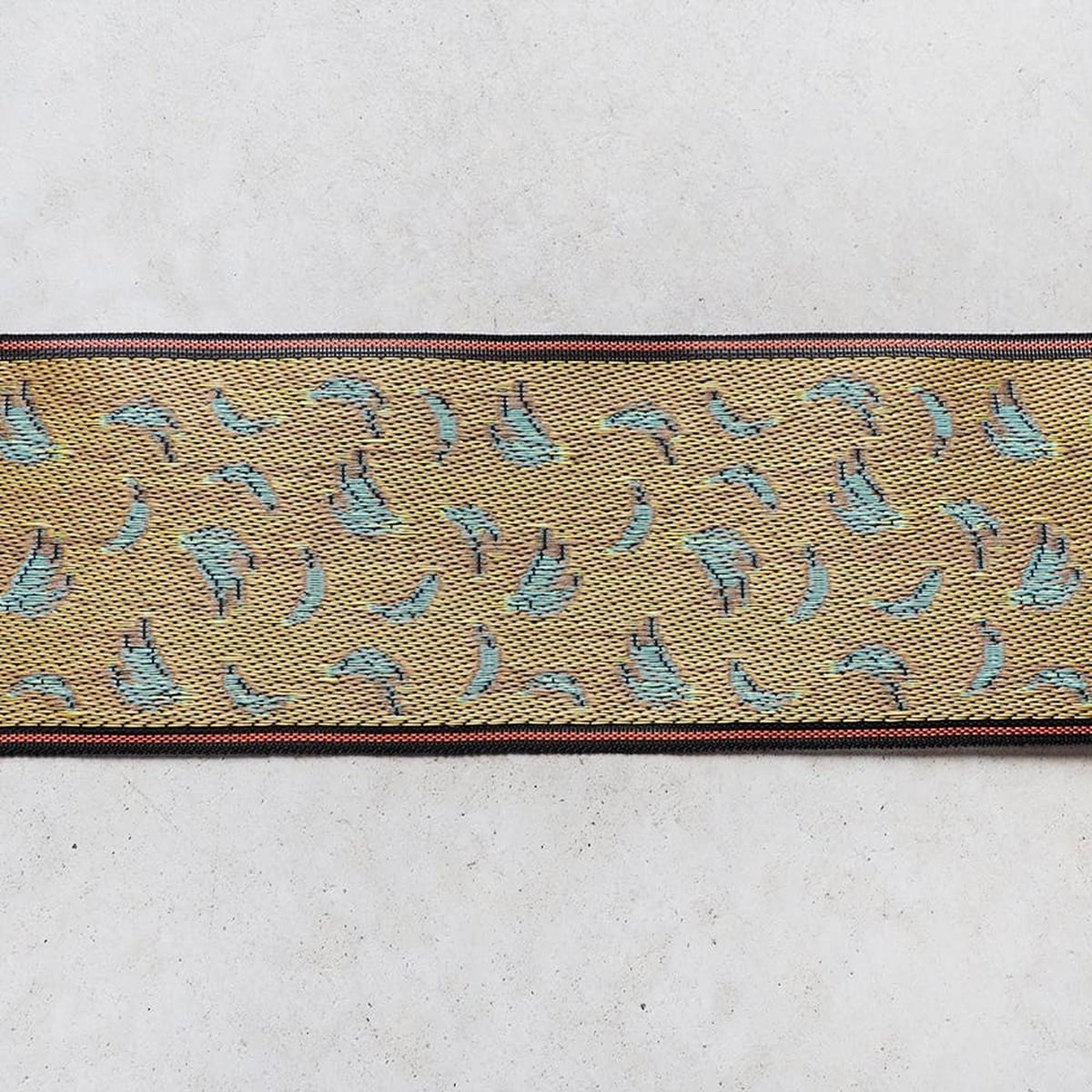a decorative fabric with a repeating pattern of small blue birds on a yellow background.
