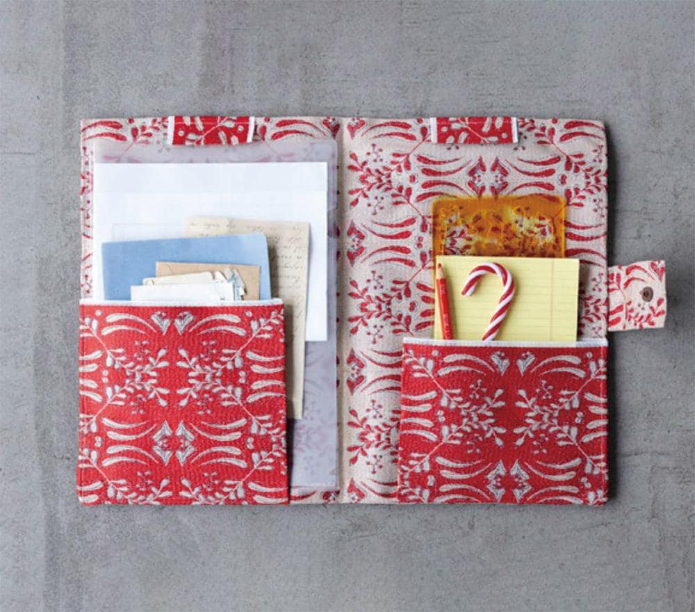 a red and white patterned pocket organizer with various items stored in it, including a candy cane, a yellow sticky note, and some papers.