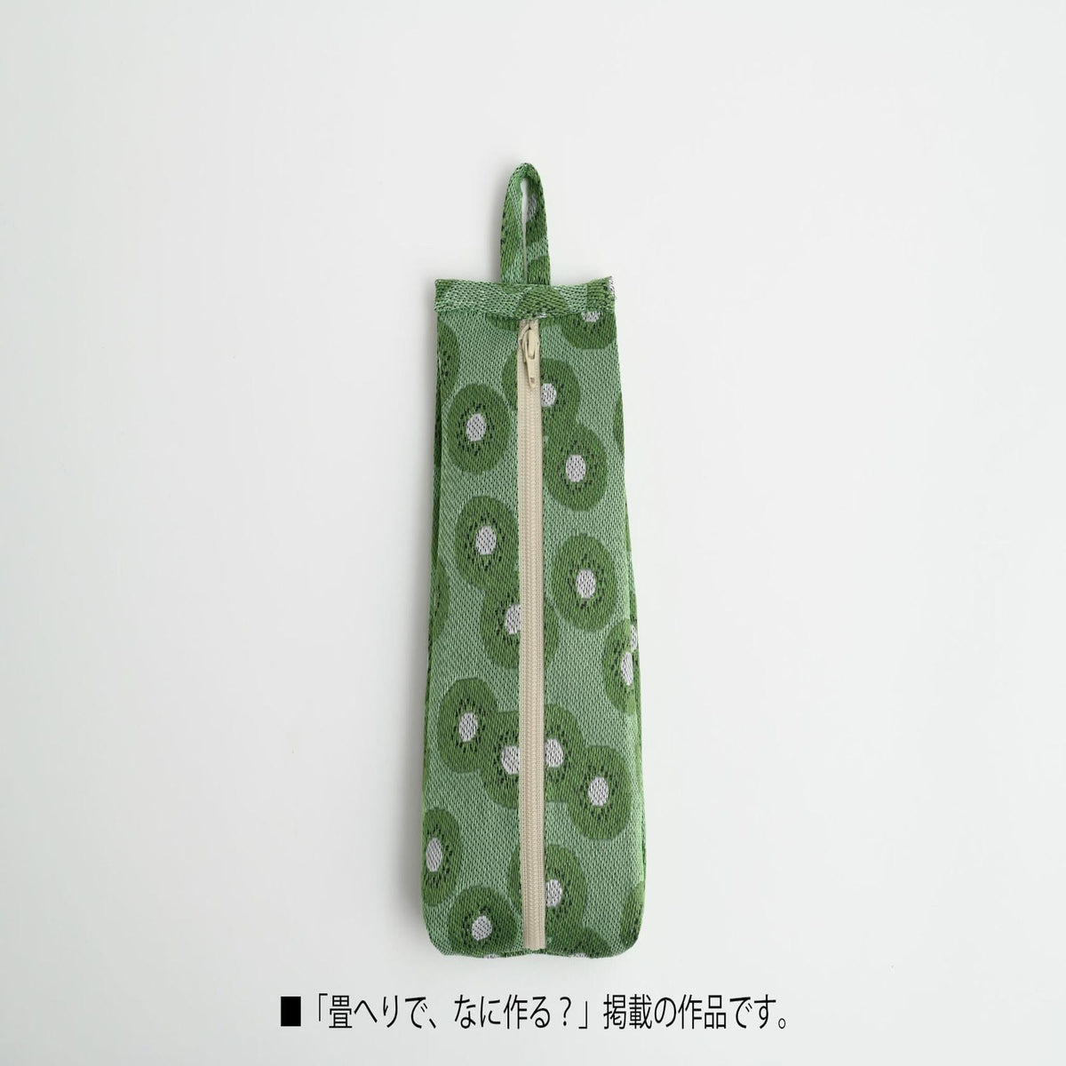 A green pencil case with a floral pattern and a zipper closure.