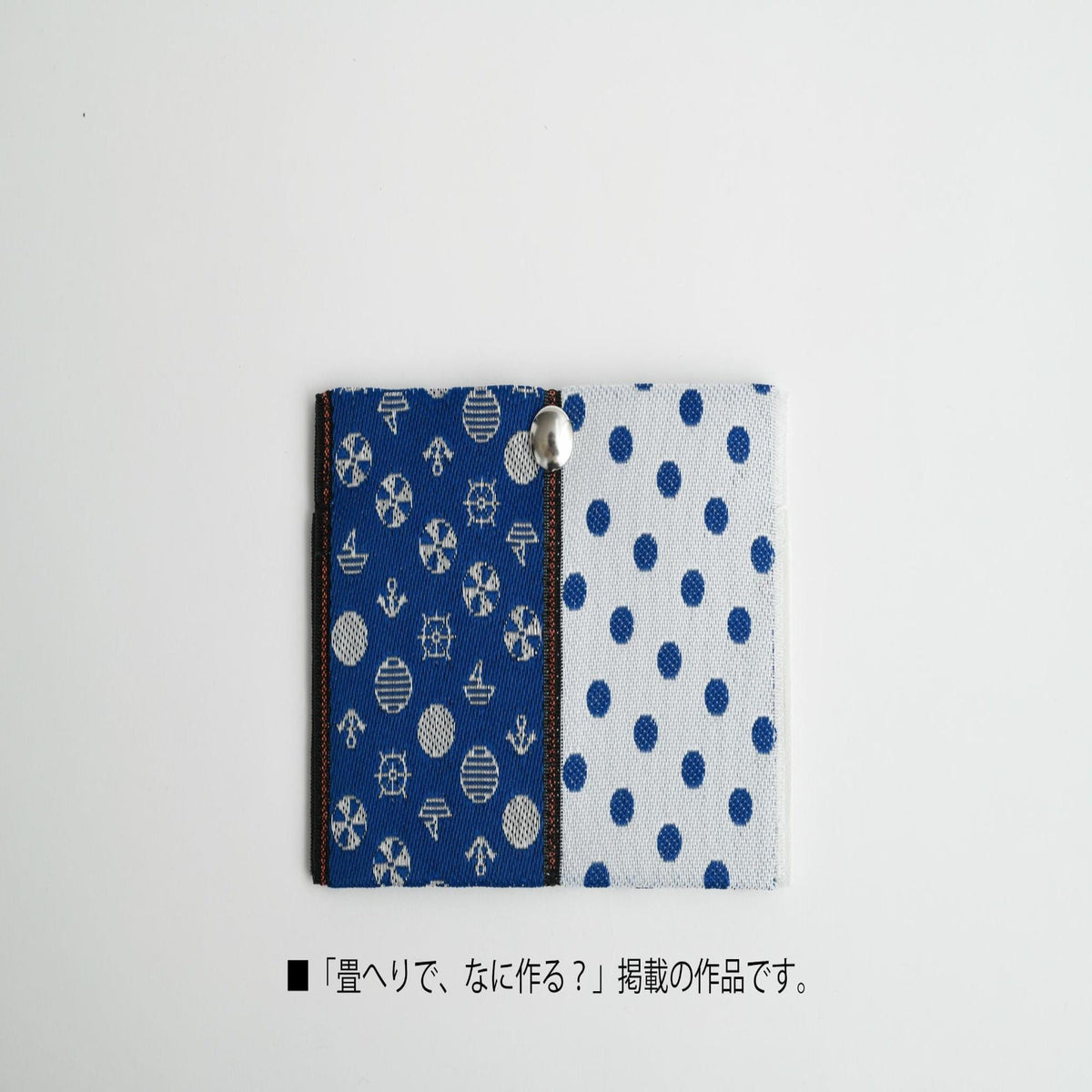A blue and white fabric with a polka dot pattern and a silver button is displayed against a white background.