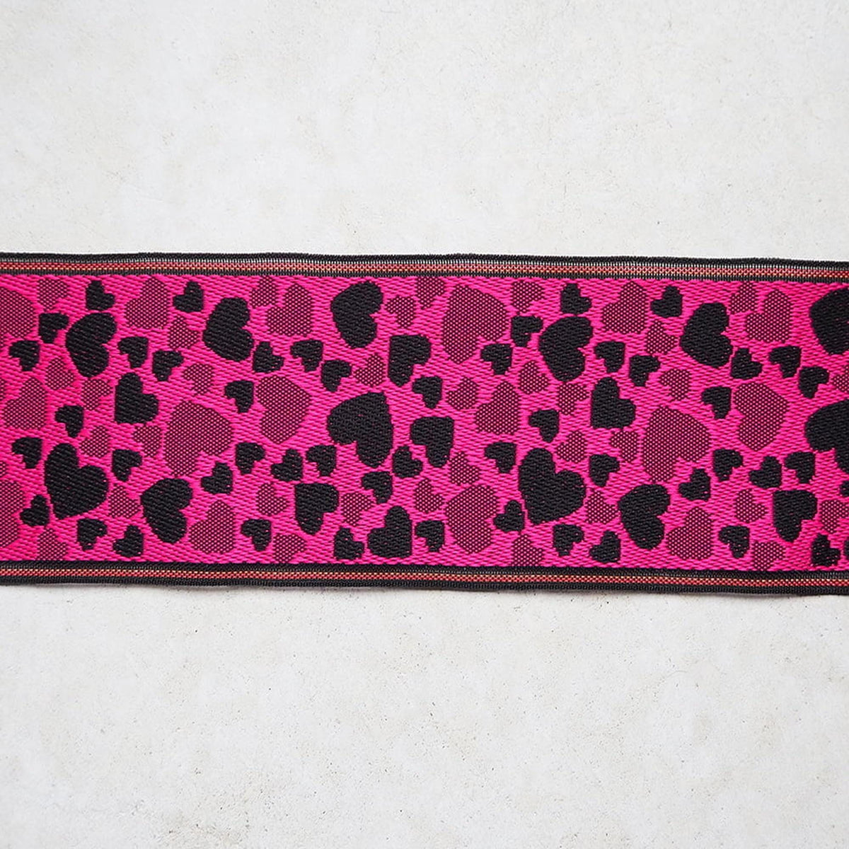 A pink and black heart-patterned fabric or textile with a black border.