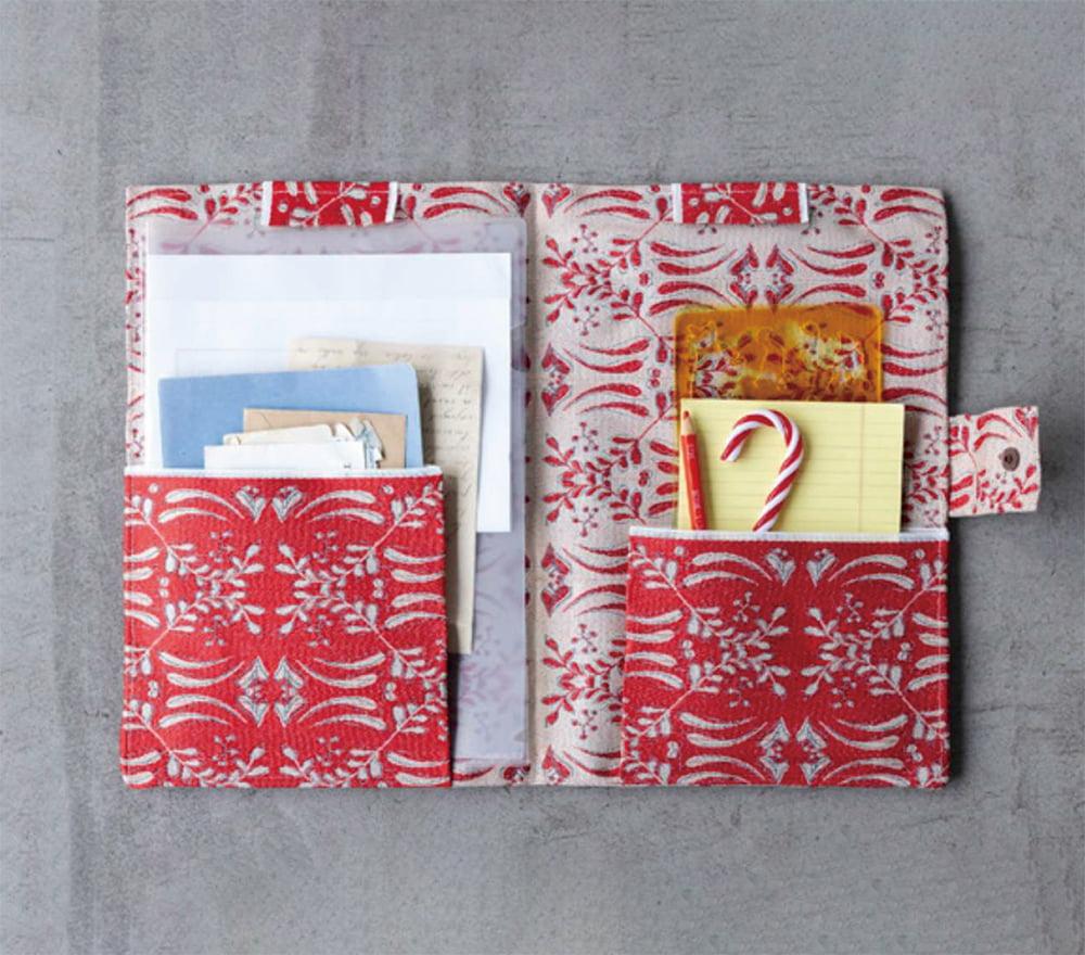 a red and white patterned pocket organizer with various items stored in it, including a candy cane, a yellow sticky note, and some papers.