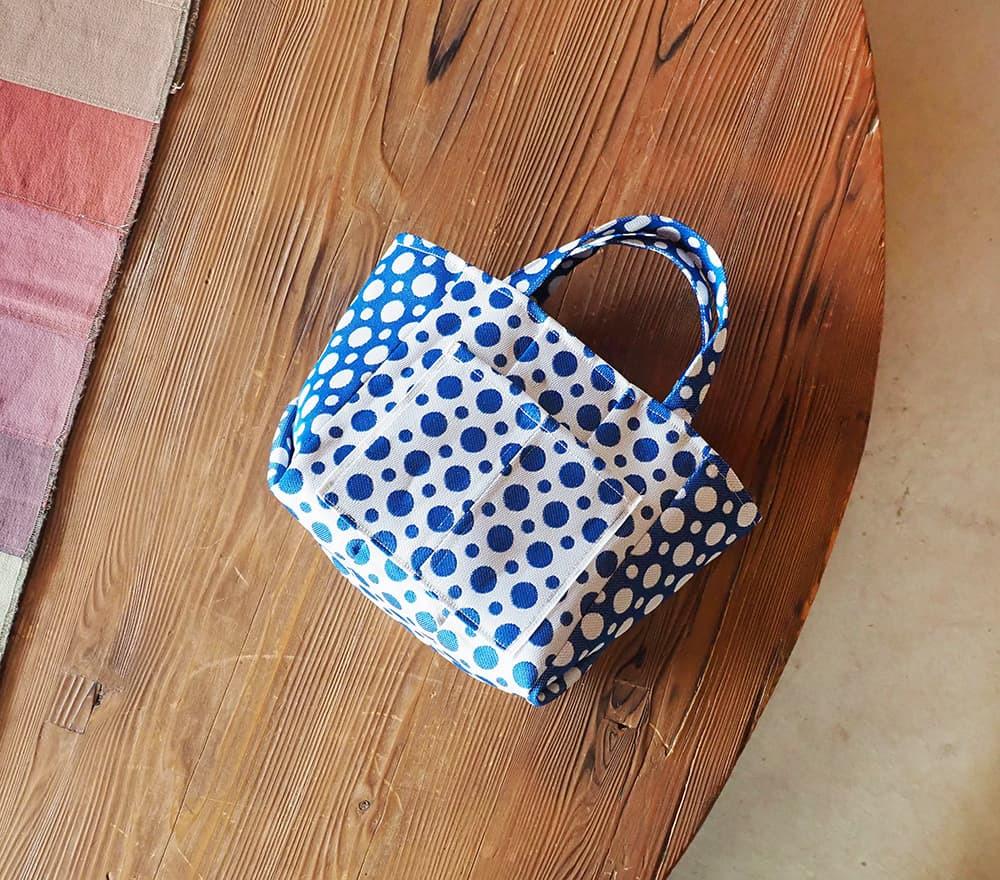 A blue and white polka dot handbag is placed on a wooden surface.