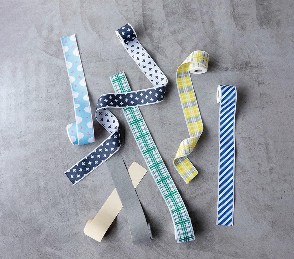 a collection of colorful and patterned fabric strips or ribbons, including plaid, striped, and polka dot designs, arranged on a gray surface.