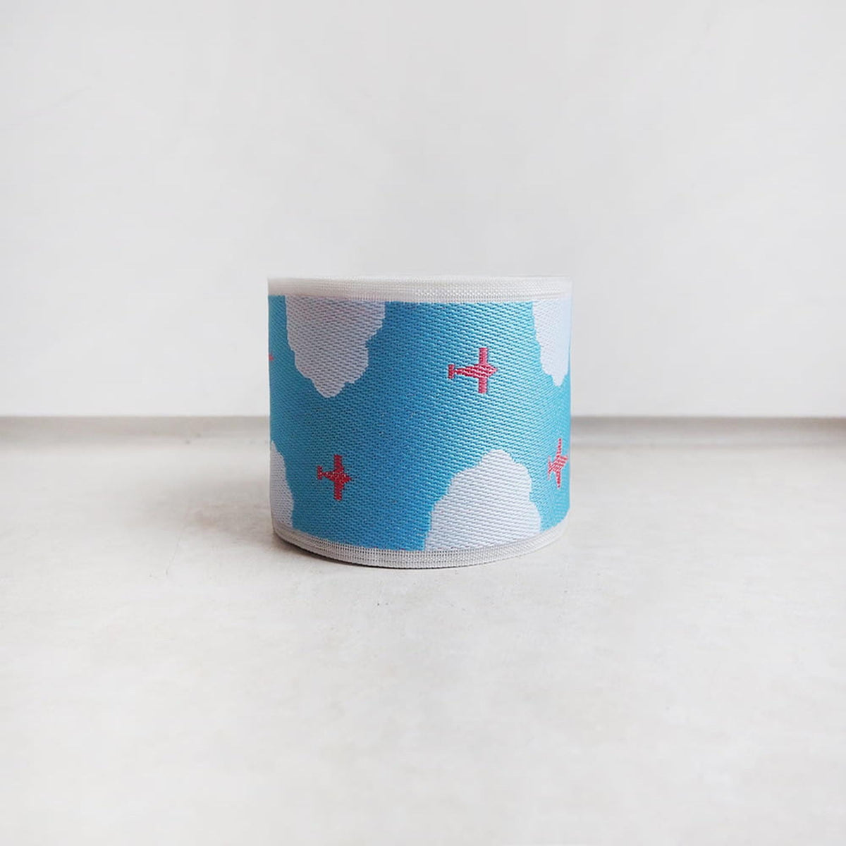 A blue and white striped object with red crosses and clouds on it, sitting on a white surface.