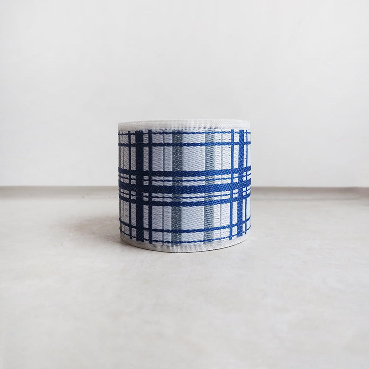 A white object with a blue and white plaid pattern, sitting on a white surface.