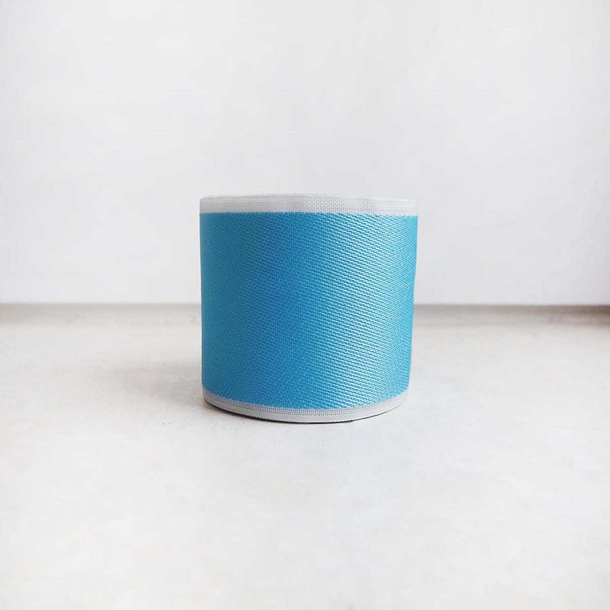 A blue and white cylindrical object, possibly a container or container, is placed on a white surface against a plain background.
