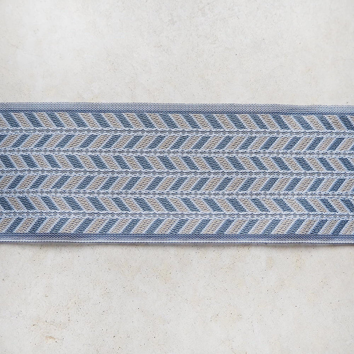 a close-up view of a decorative blue and gray patterned fabric or textile, which appears to be a decorative border or trim.