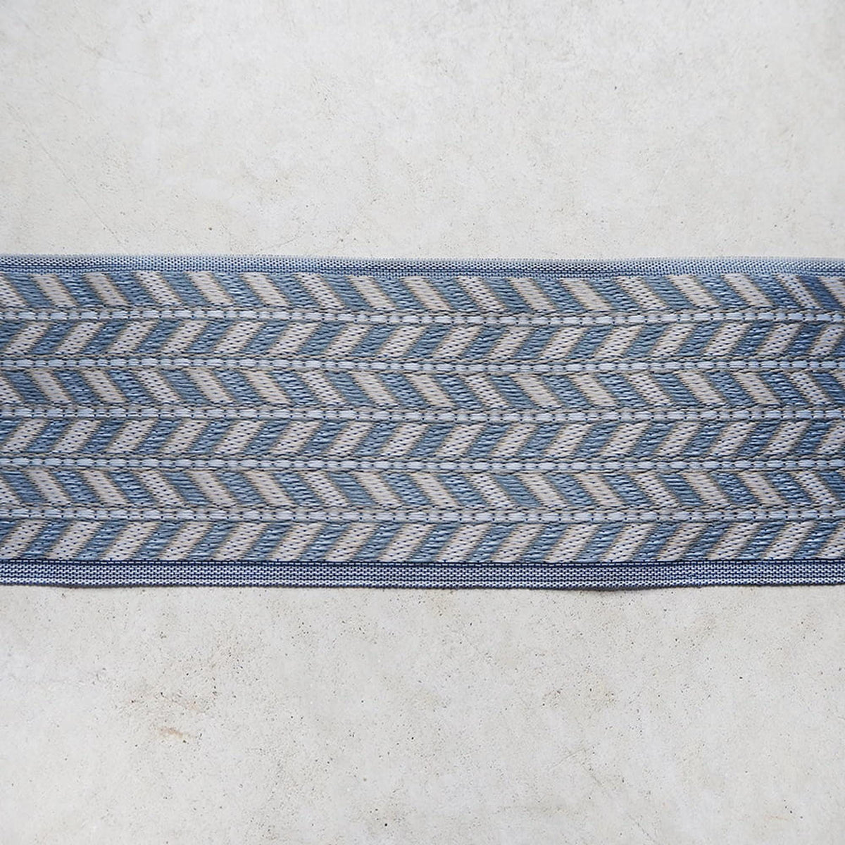 a close-up view of a blue and white chevron-patterned fabric or textile, which appears to be a decorative trim or border.