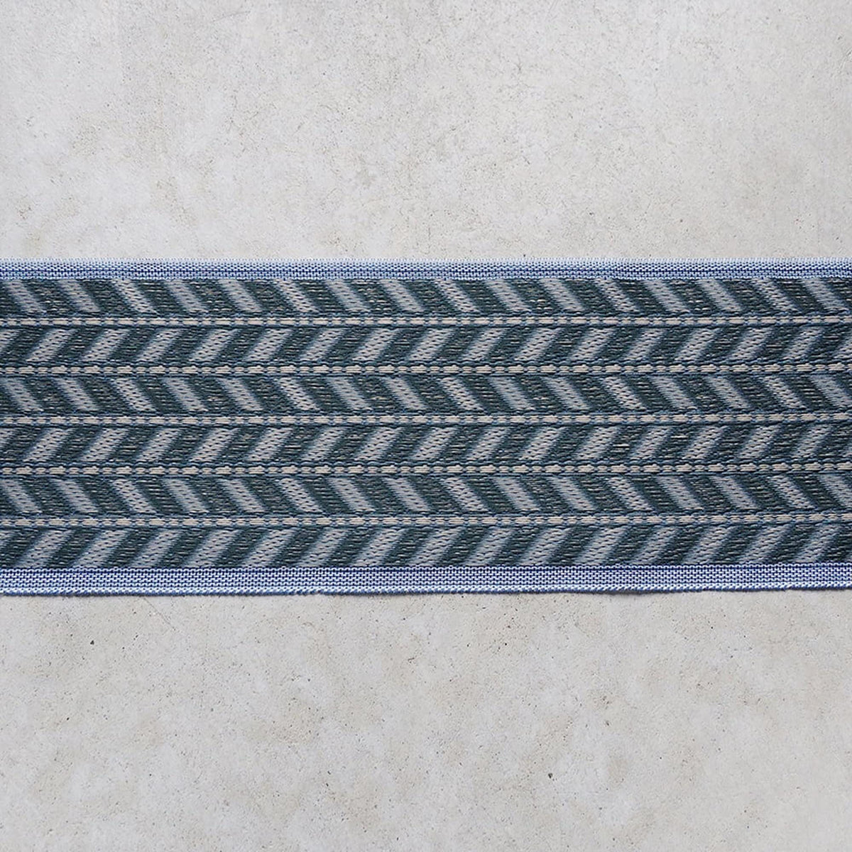 a close-up view of a decorative textile with a repeating pattern of diagonal lines in shades of blue and gray.