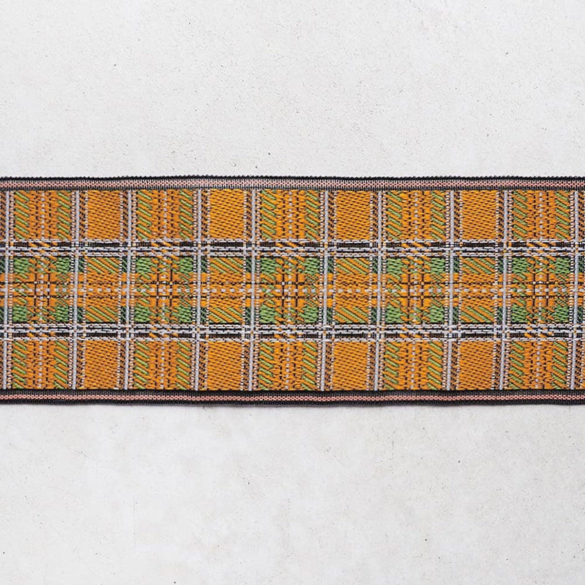 a close-up view of a decorative fabric with a repeating pattern of orange and green squares.