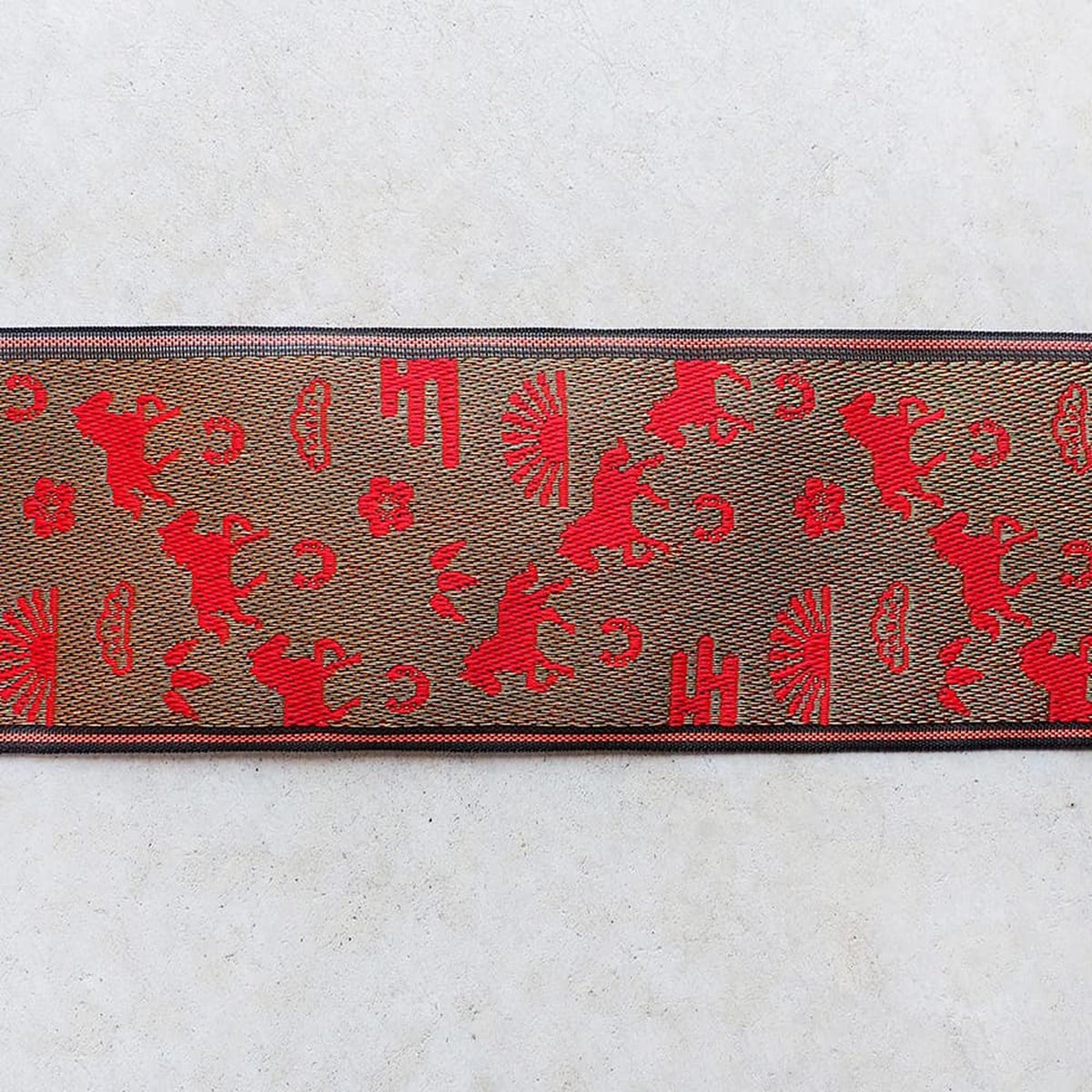 a brown and red patterned fabric with various red animal silhouettes and other decorative elements.