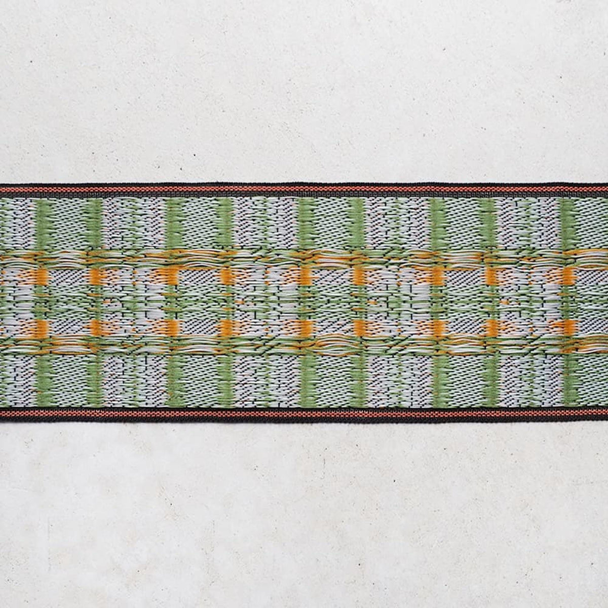 a close-up view of a colorful woven textile with a repeating pattern of green, orange, and white stripes or lines.