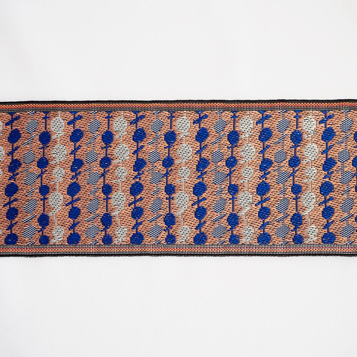 a close-up view of a decorative textile with a repeating pattern of blue and orange circles and lines.