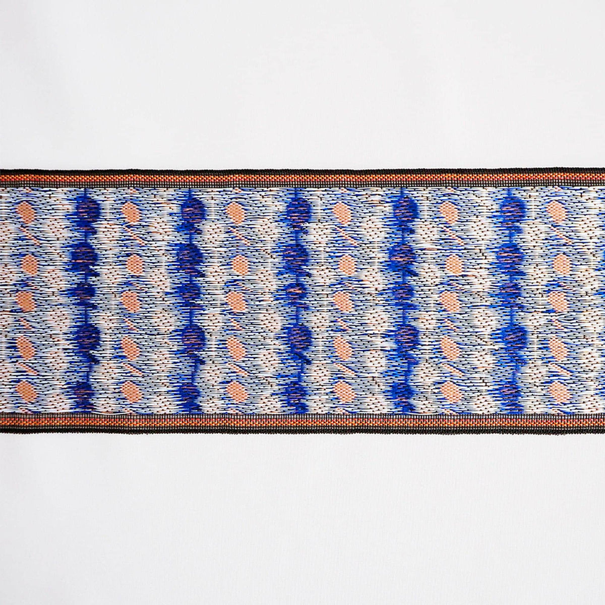 a close-up view of a decorative textile with a repeating pattern of blue and white stripes and small orange dots.