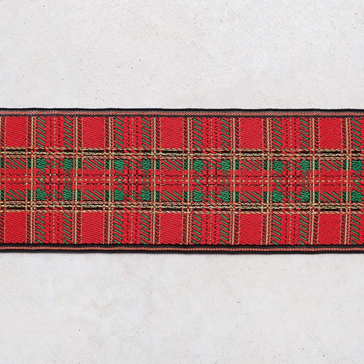 A close-up view of a red and green plaid fabric with a repeating pattern of squares and rectangles.