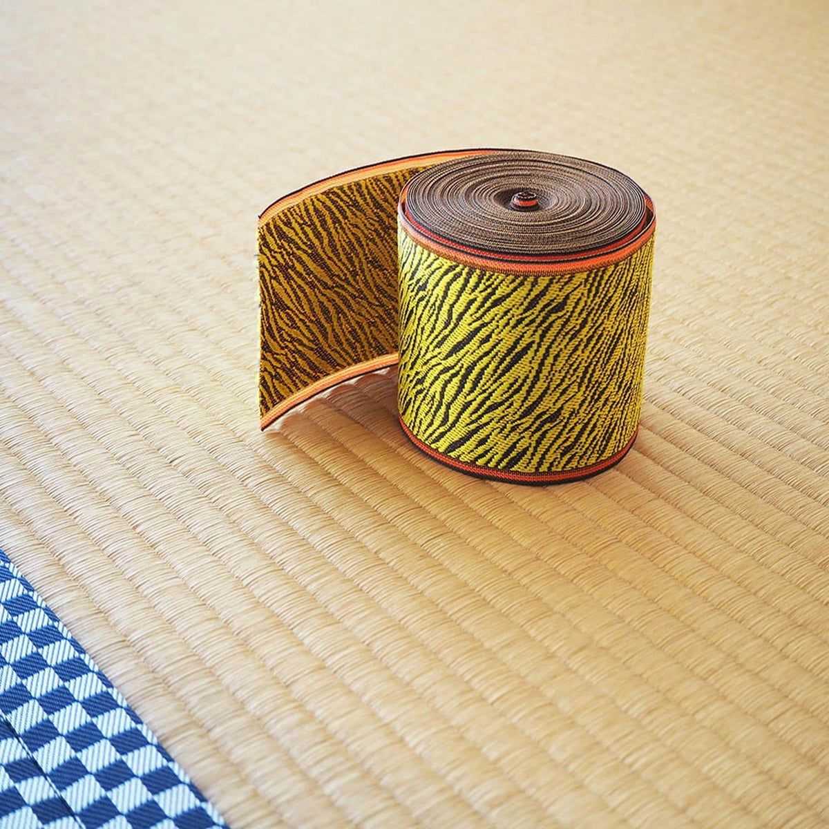 A roll of decorative fabric with a zebra print pattern is placed on a woven mat.