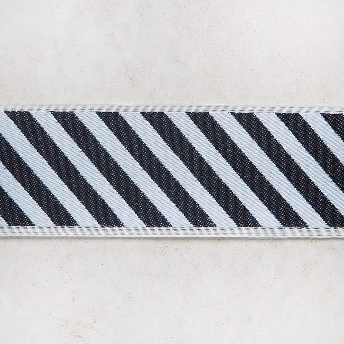 A close-up view of a black and white striped fabric or ribbon, with the diagonal stripes in black and white.