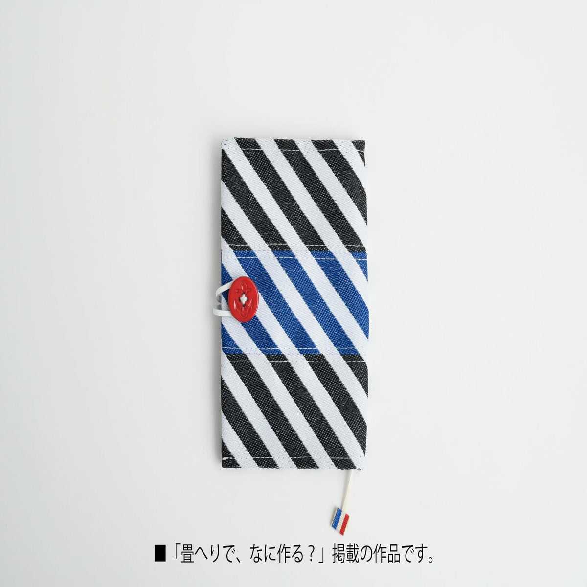A black and white striped wallet with a red button, placed on a white background.