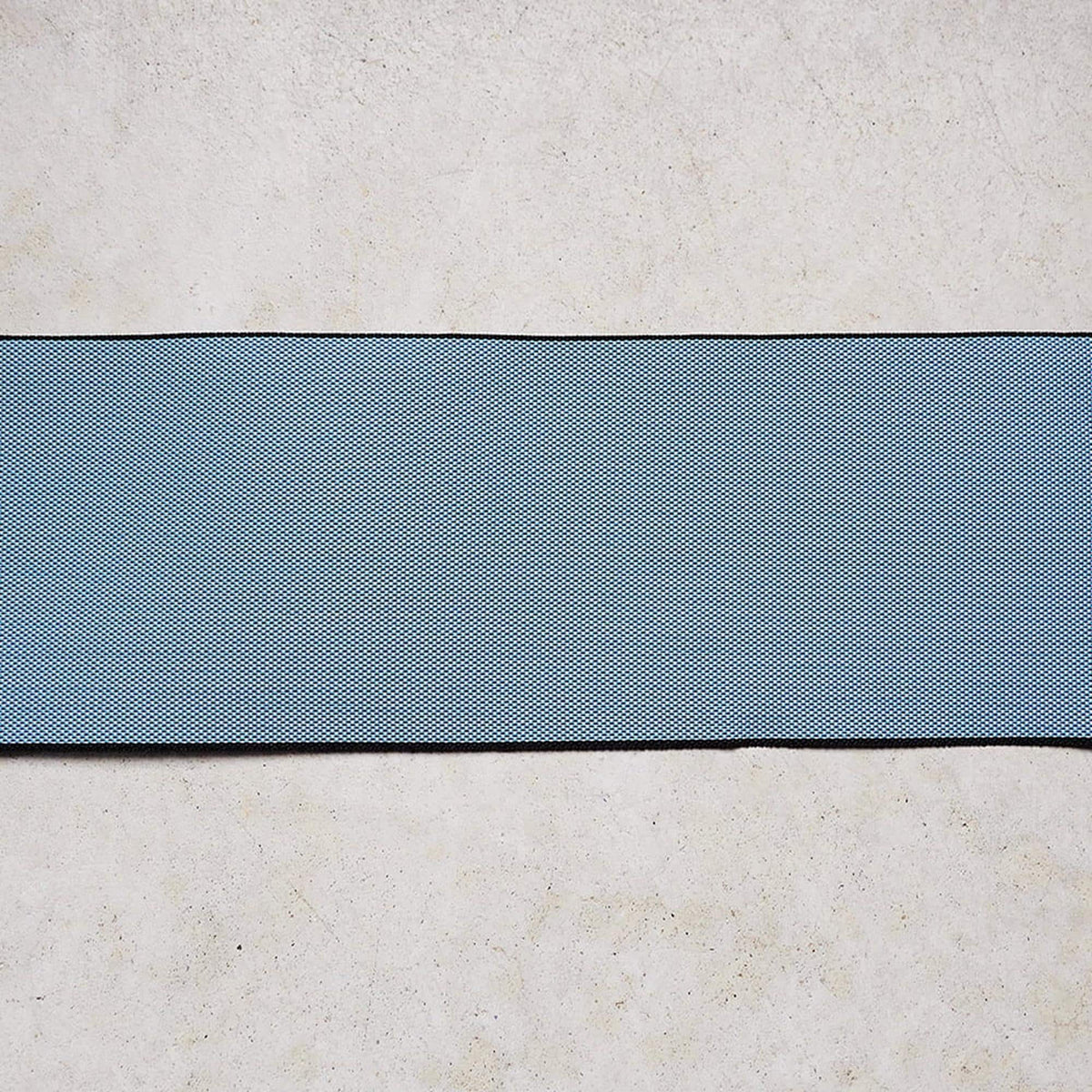 a blue and white striped fabric or material, possibly a piece of clothing or textile, placed on a plain, light-colored surface.