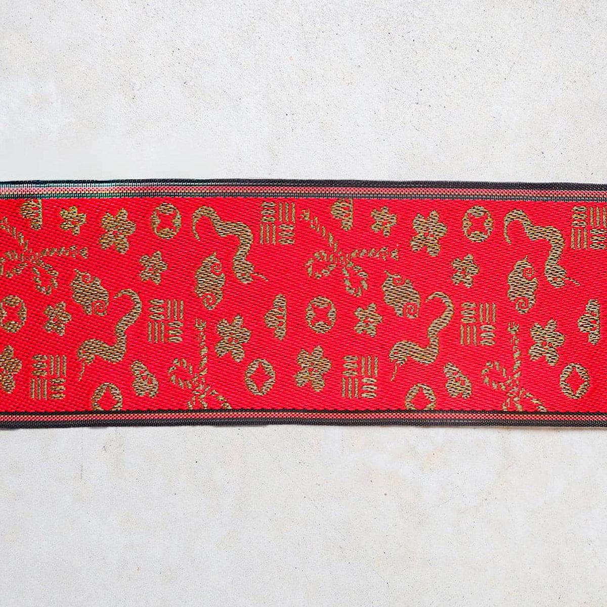 a red fabric with a gold pattern, including various shapes and designs.