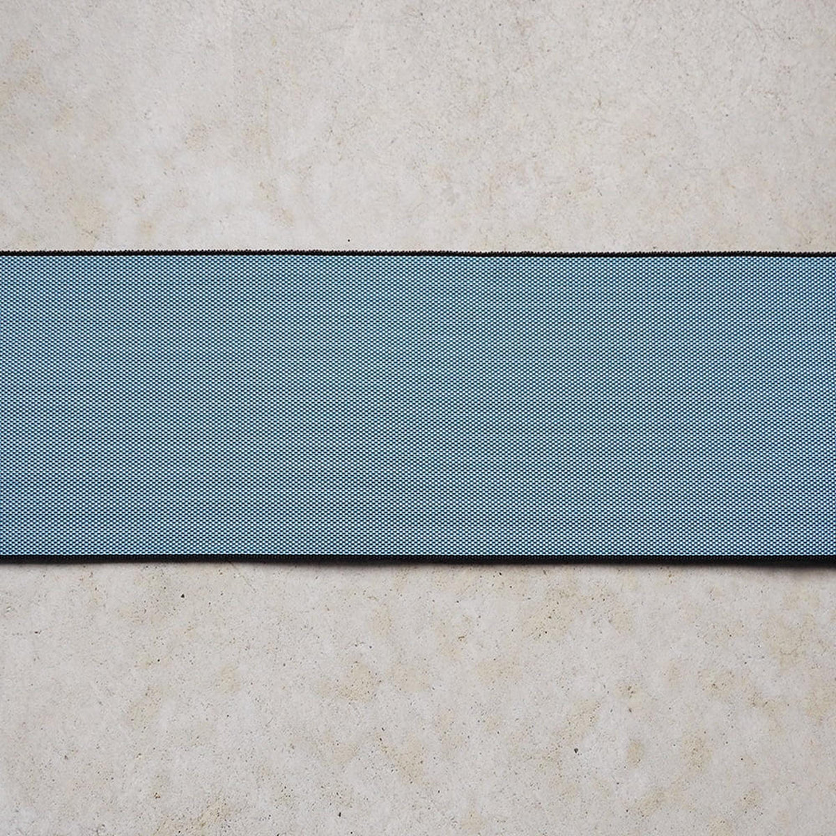 a blue and black striped fabric or material laid out on a light-colored surface, such as a concrete floor or wall.