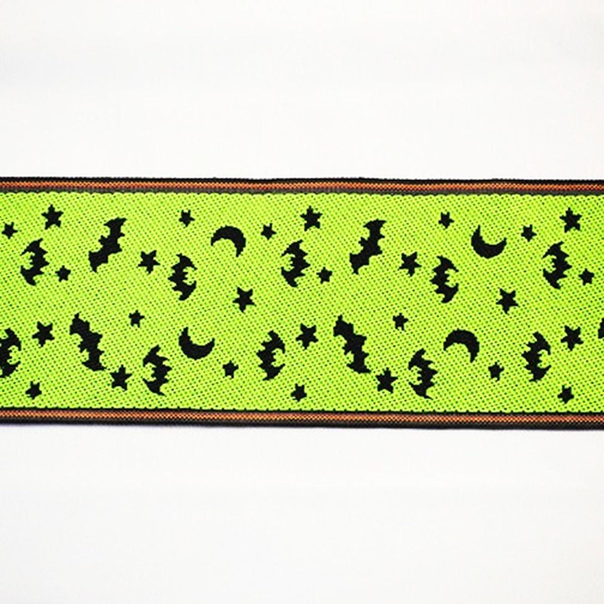 a green fabric with a repeating pattern of bats, crescent moons, and stars on it.