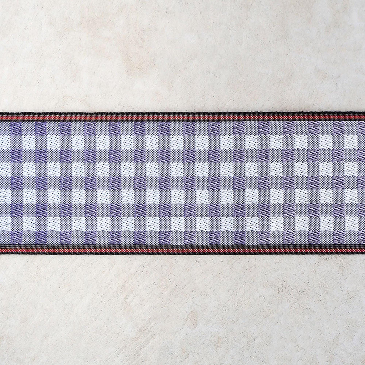 a close-up view of a checkered pattern on a fabric, with a red border around it.