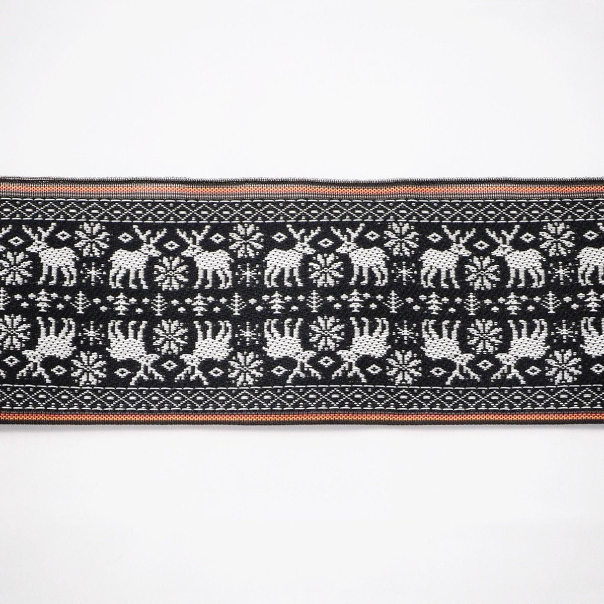 a black and white patterned fabric with a repeating design of deer and snowflakes.