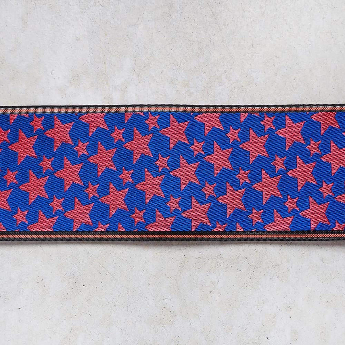 a close-up view of a fabric with a repeating pattern of red and blue stars on a white background.