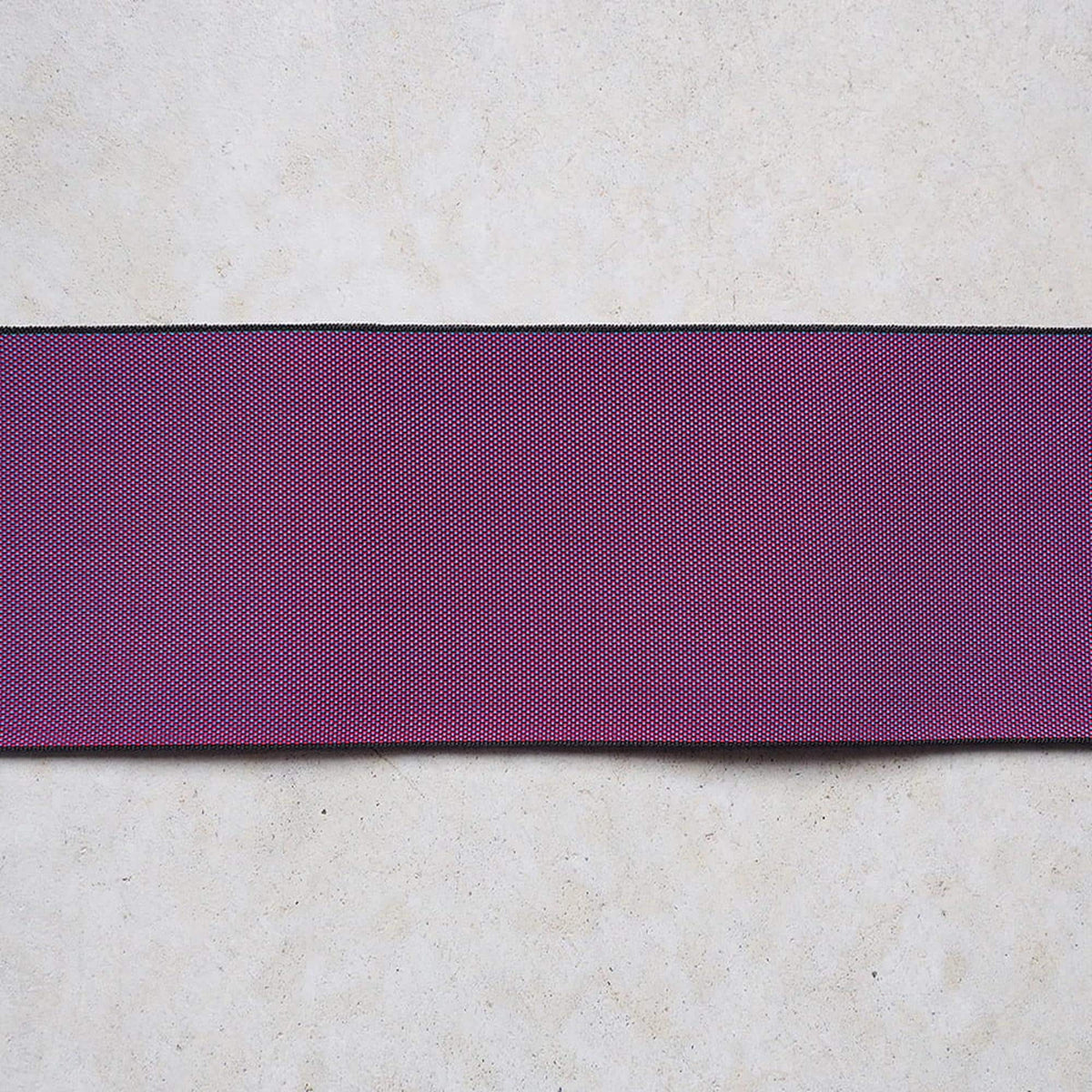 a single, horizontal purple fabric or ribbon against a plain, light-colored background.