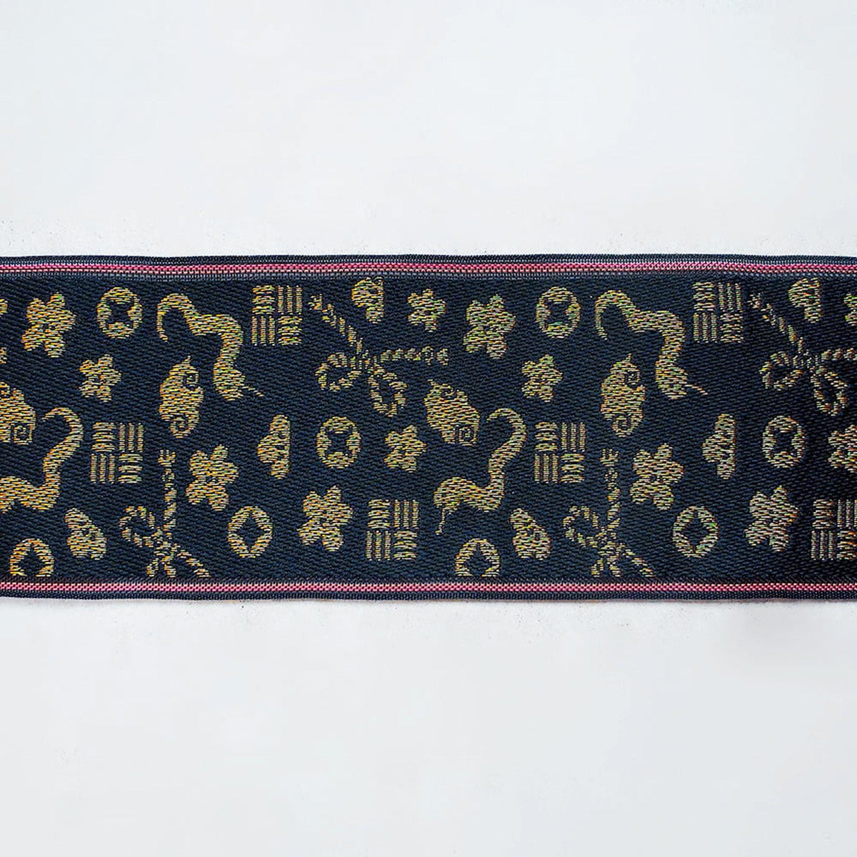 a decorative fabric with a repeating pattern of gold and black shapes, including flowers, leaves, and geometric designs.