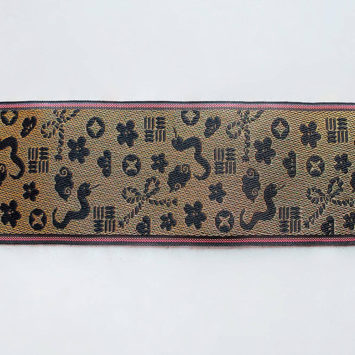 a decorative fabric with a repeating pattern of black and gold designs, including floral and geometric shapes.