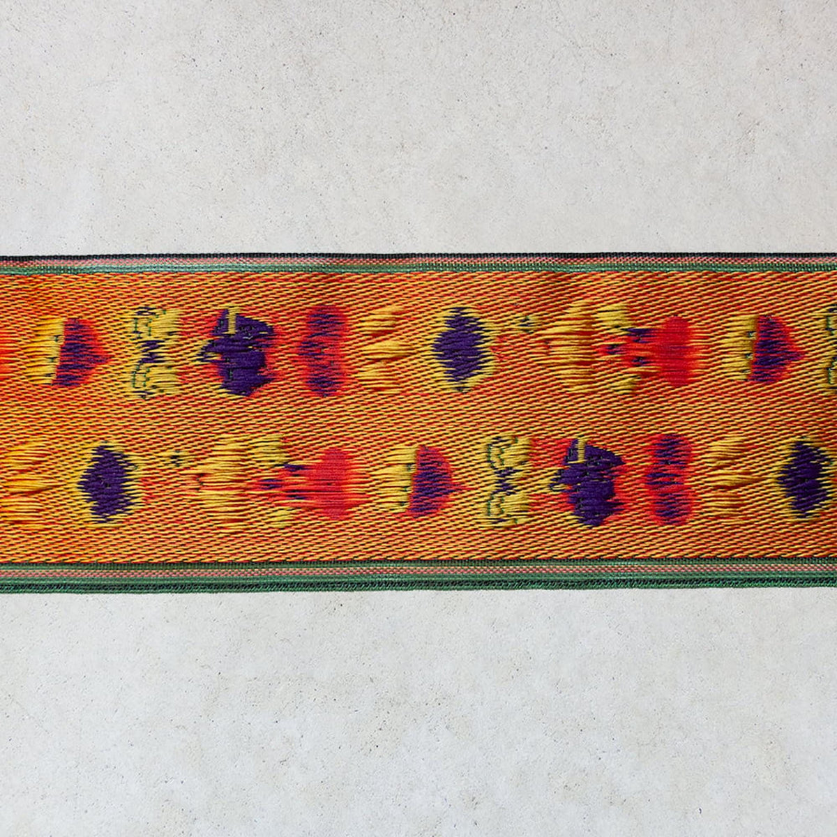 a vibrant, colorful textile with a repeating pattern of orange and yellow flowers on a green border.