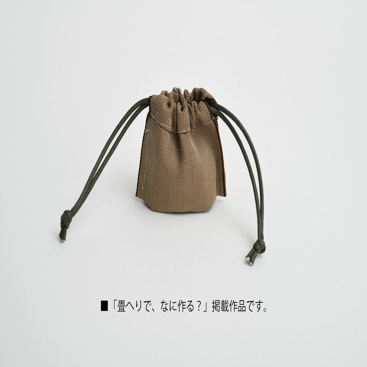 A small brown bag with a drawstring closure and two green strings, sitting on a white background.