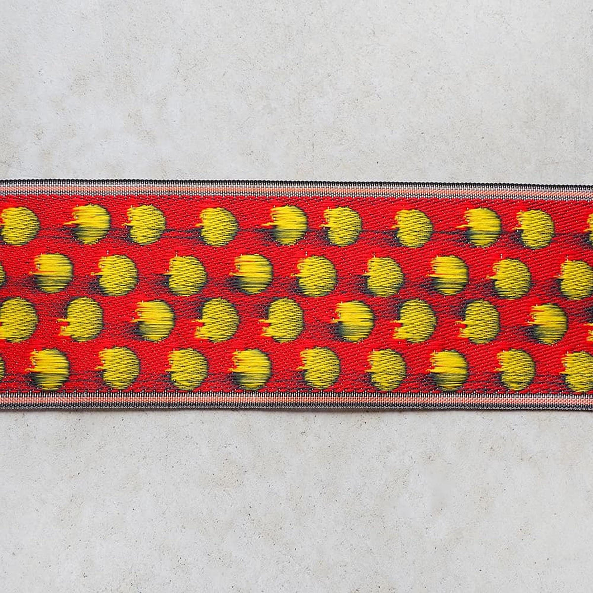 a red and yellow patterned fabric with a repeating design of yellow circles on a red background.