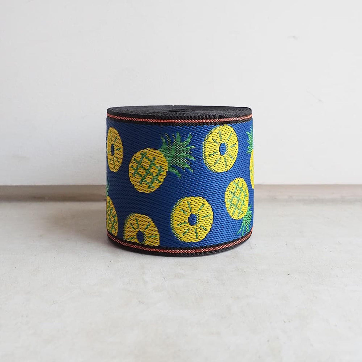 A blue and yellow patterned object, resembling a piece of fabric or a decorative item, is placed on a white surface against a plain background.