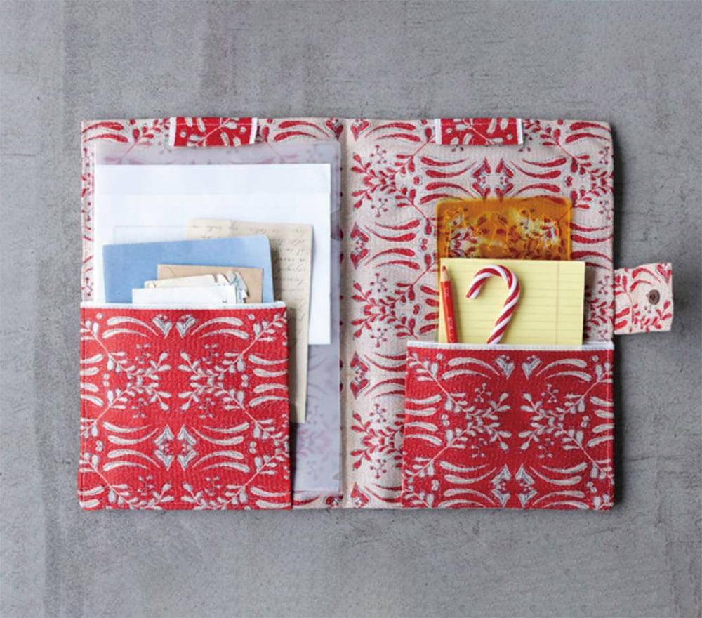 a red and white patterned pocket organizer with various items stored in it, including a candy cane, a yellow sticky note, and some papers.