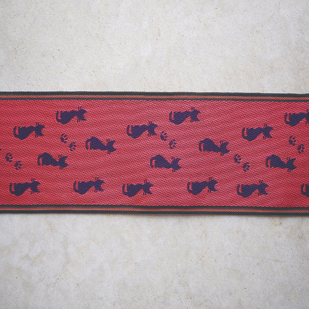 a red and black patterned fabric with a repeating design of black cat silhouettes on a red background.