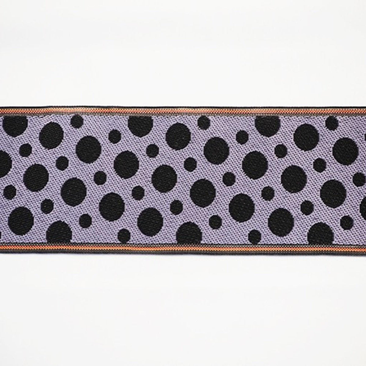 a close-up view of a fabric with a repeating pattern of black circles on a purple background.
