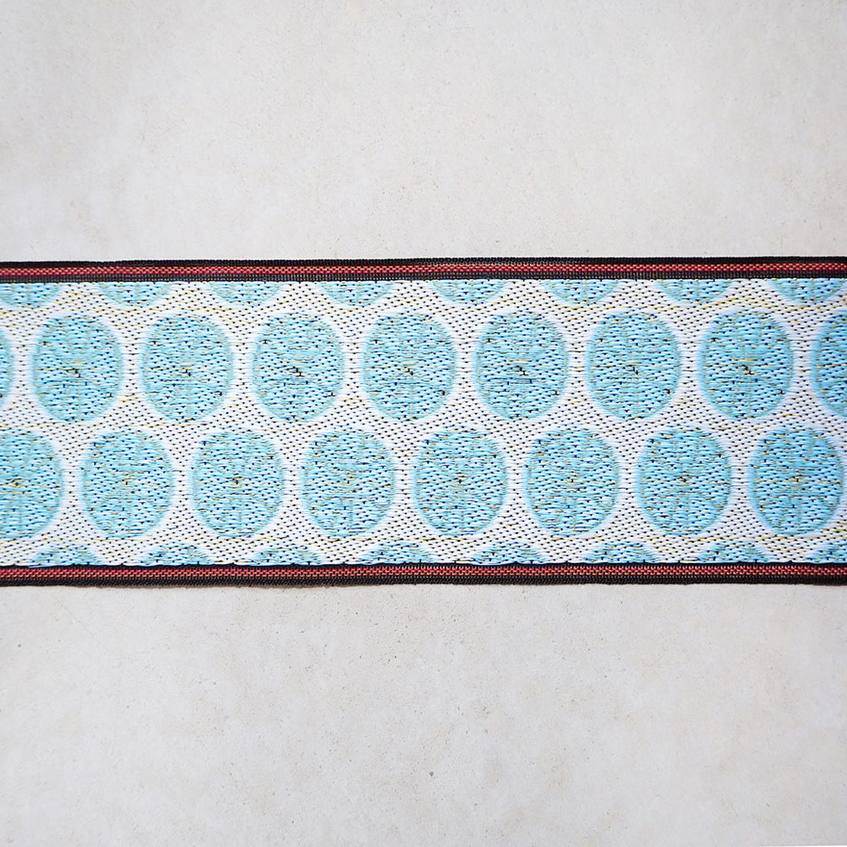 a close-up view of a decorative fabric with a repeating pattern of blue circles on a white background.