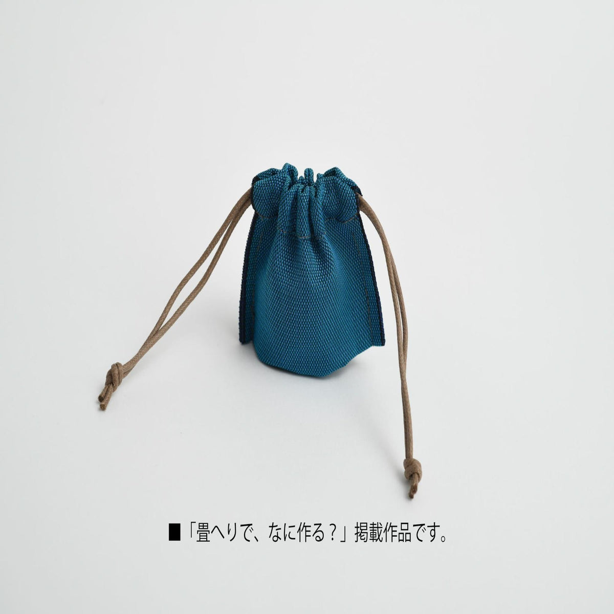 A small blue mesh bag with brown strings, placed on a white background.