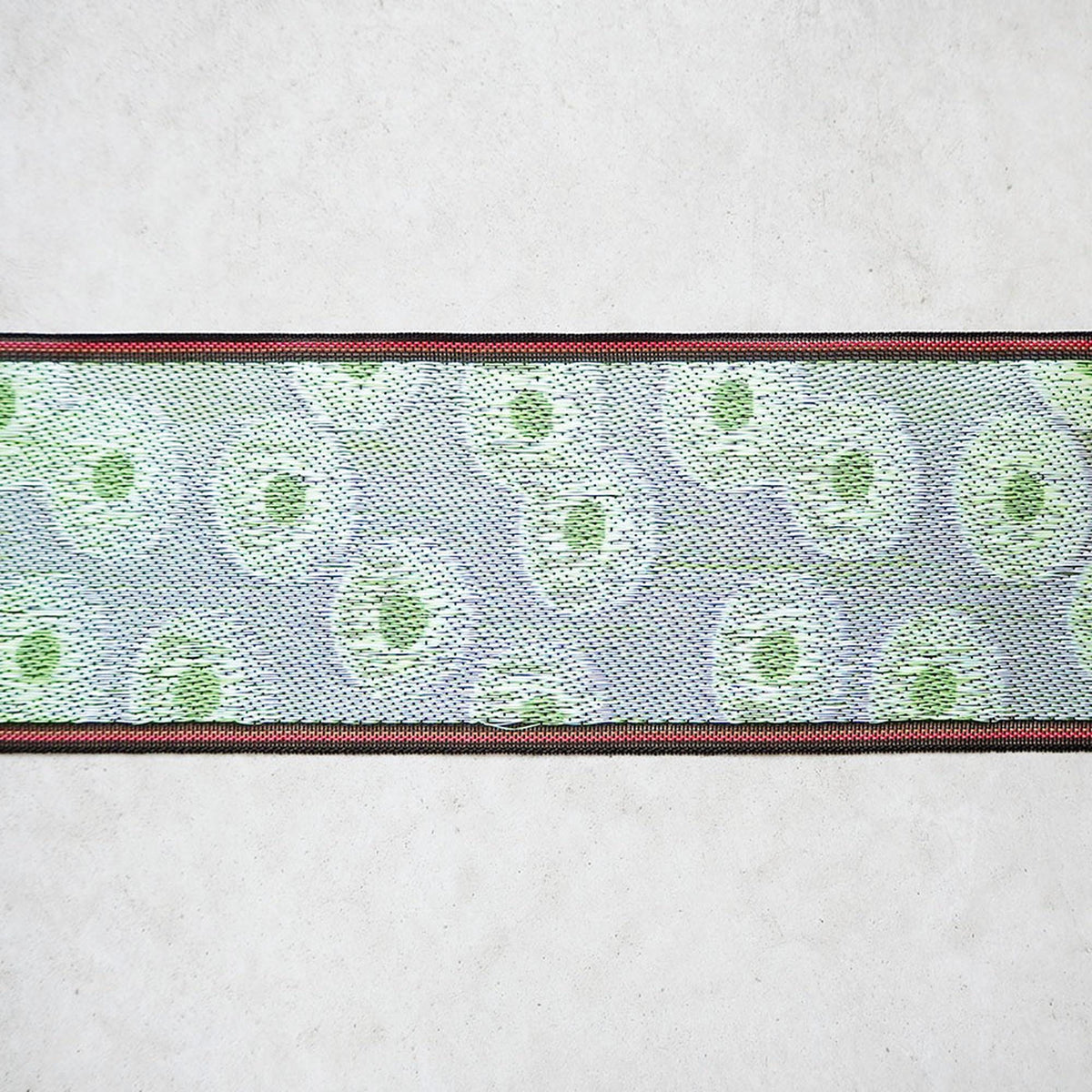 a close-up view of a decorative ribbon with a repeating pattern of green circles on a white background.