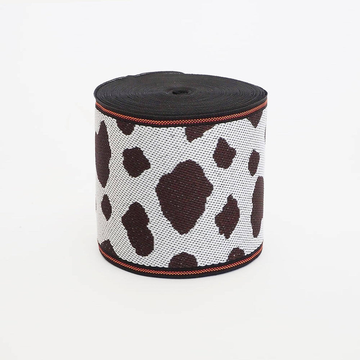 A cylindrical object with a black and white spotted pattern, resembling a piece of fabric or a decorative item.