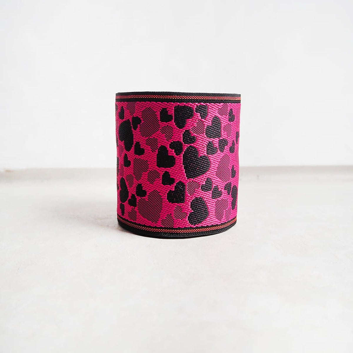 A pink and black heart-patterned object, possibly a piece of clothing or accessory, is sitting on a white surface.