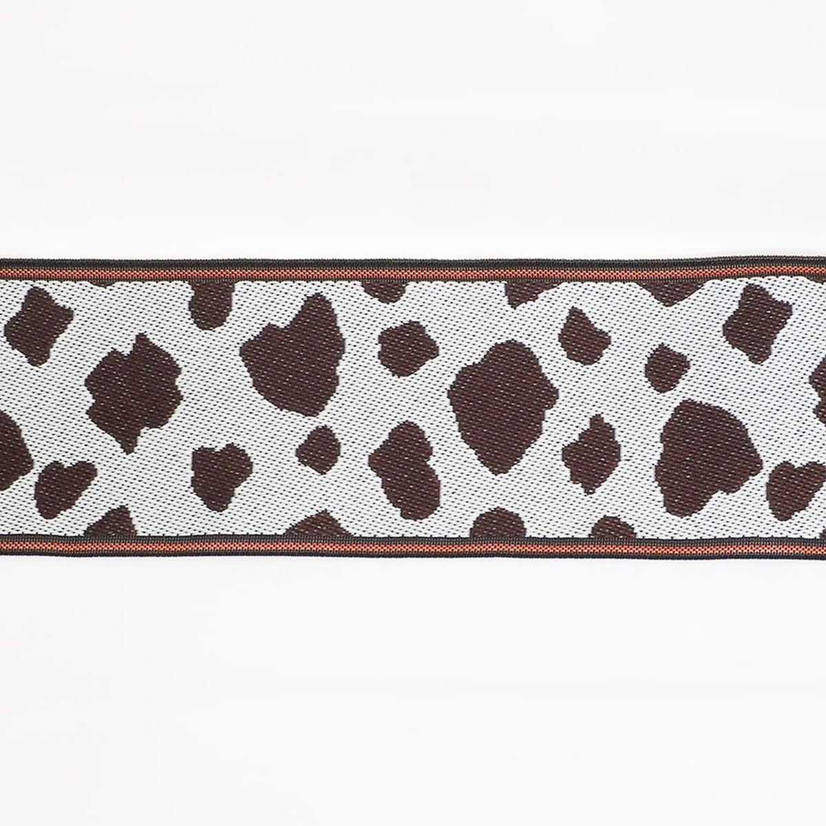 A close-up view of a fabric with a cow print pattern, featuring a mix of brown and white spots.