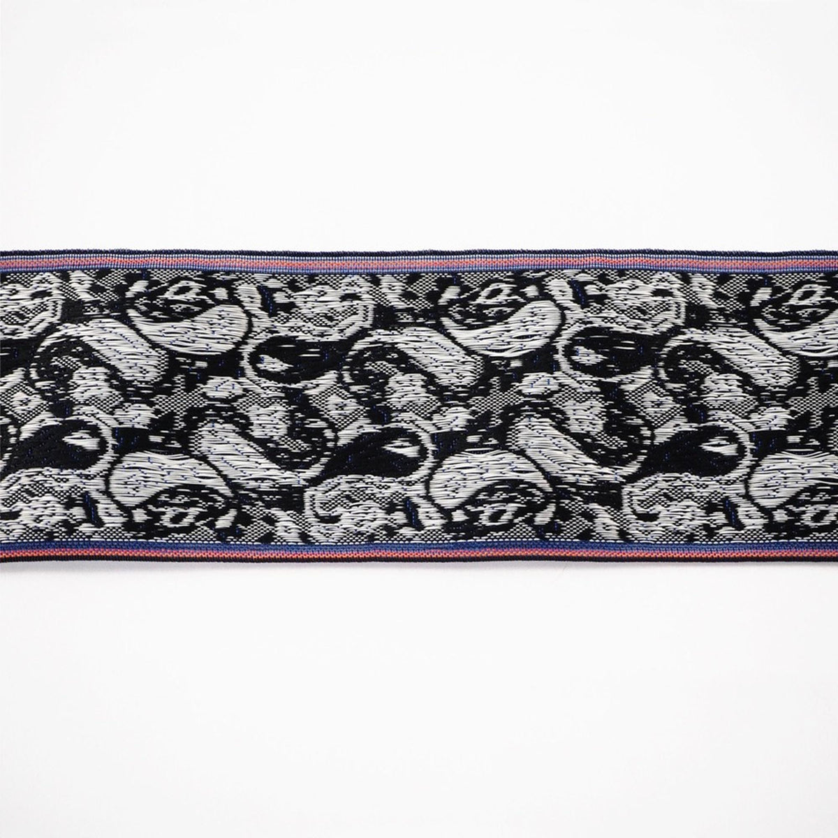 a close-up view of a decorative textile with a repeating pattern of black and white swirls and shapes.