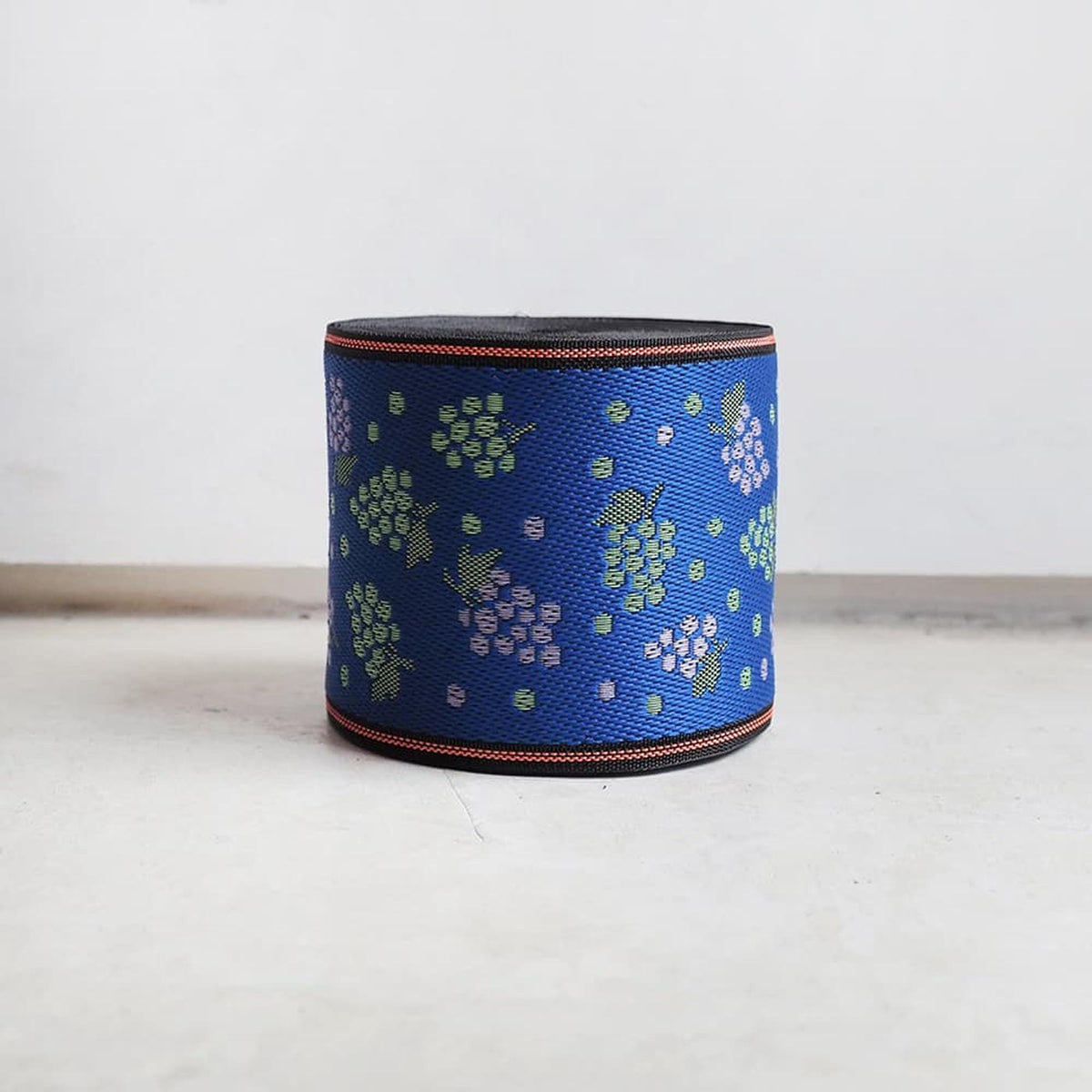 A blue and green patterned container or bag is sitting on a white surface.