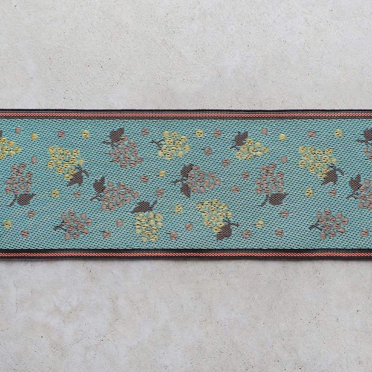 a close-up view of a blue fabric with a repeating pattern of yellow and brown flowers or leaves.