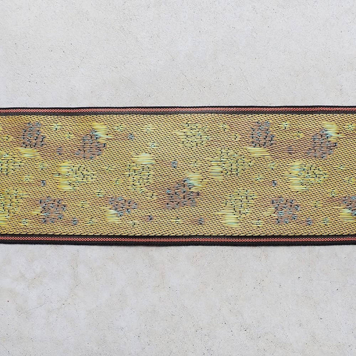 a decorative fabric with a yellow and green pattern, featuring small circles or dots on a beige background.